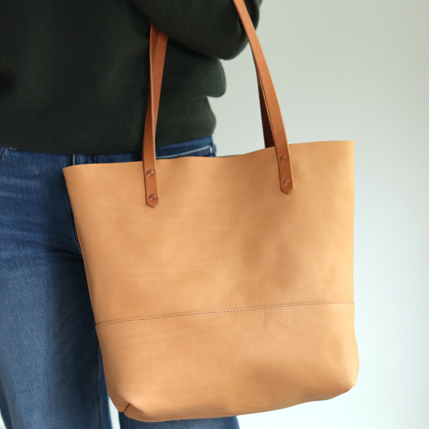 Beige vacchetta leather tote bag handcrafted from full-grain vegetable-tanned leather with hand-burnished straps and copper rivets.