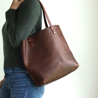 Woman wearing dark brown leather tote bag handcrafted with italian vegetable tanned leather and copper rivets