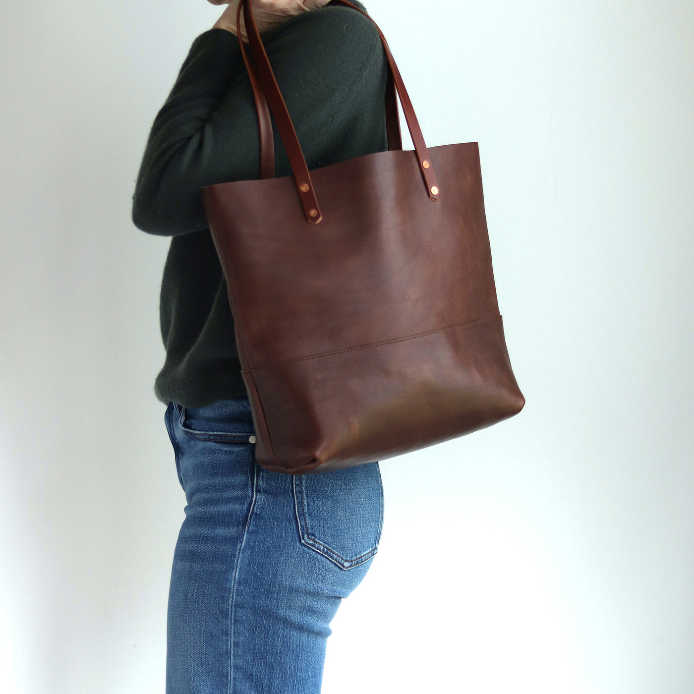 Dark brown Italian leather tote bag with hand-burnished straps and copper rivets, handcrafted in Vermont.