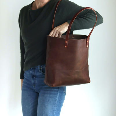 Woman wearing minimalist classic brown large leather tote handcrafted with Italian vegetable tanned leather.