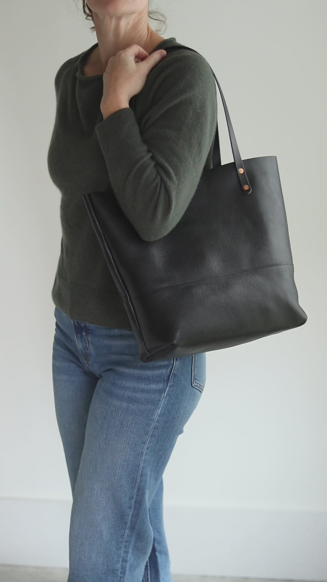 All-black Italian pebbled leather tote with matching black bridle straps and copper rivets.
