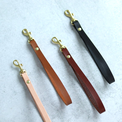 Leather wrist straps handmade with vegetable tanned leather and brass and gold hardware. Add a slim leather wrist strap to your clutch bag, by Juliette Rose Designs. 4 colors are available in black, cognac brown, tan, and natural beige.