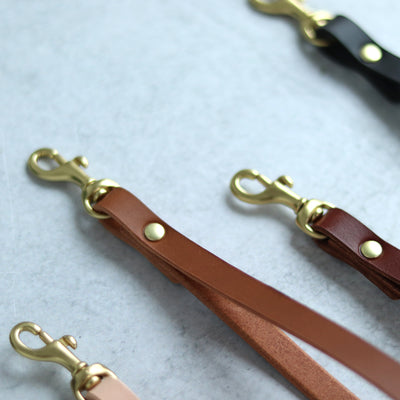 Leather wrist straps handmade with vegetable tanned leather and brass and gold hardware. Add a slim leather wrist strap to your clutch bag, by Juliette Rose Designs. 4 colors are available in black, cognac brown, tan, and natural beige.